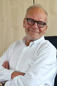 Kollege sitzt auf Stuhl vor Schrankwand