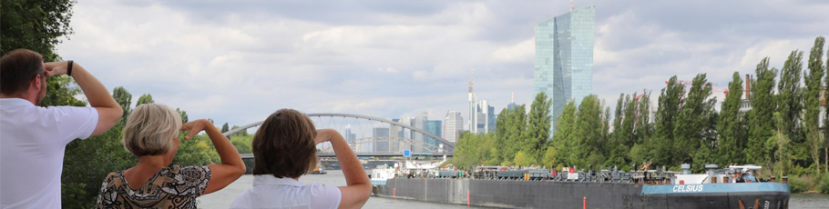 Team aus Frankfurt steht am Main mit Blick Richtung Frankfurter Skyline